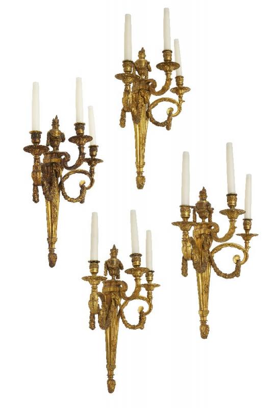 A set of four Louis XVI style three branch wall lights, 20th century, each with urn form finial to a tapering fluted back plate