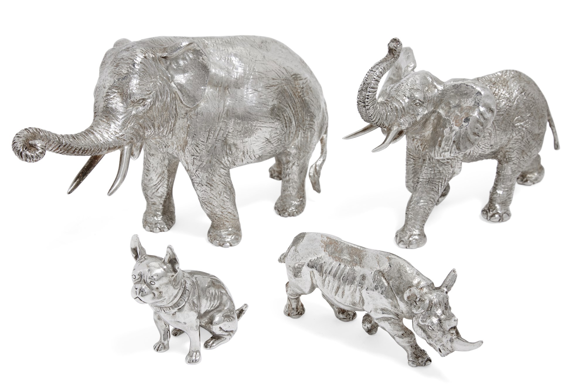 Two silver elephant ornaments, both depicted with trunks raised, together with two smaller silver animal models